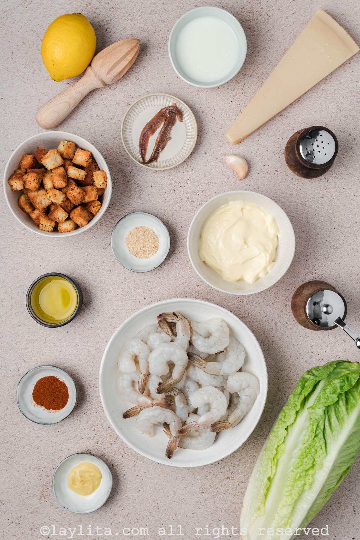 Ingredients needed to make shrimp Caesar salad on a kitchen counter