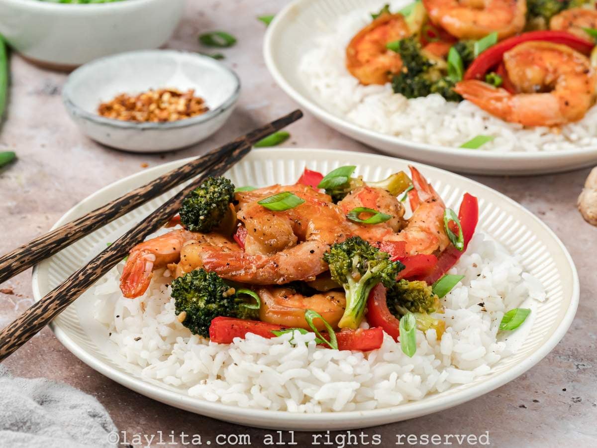 Side view of a bowl of shrimp broccoli stir fry with rice, with another bowl in the background.