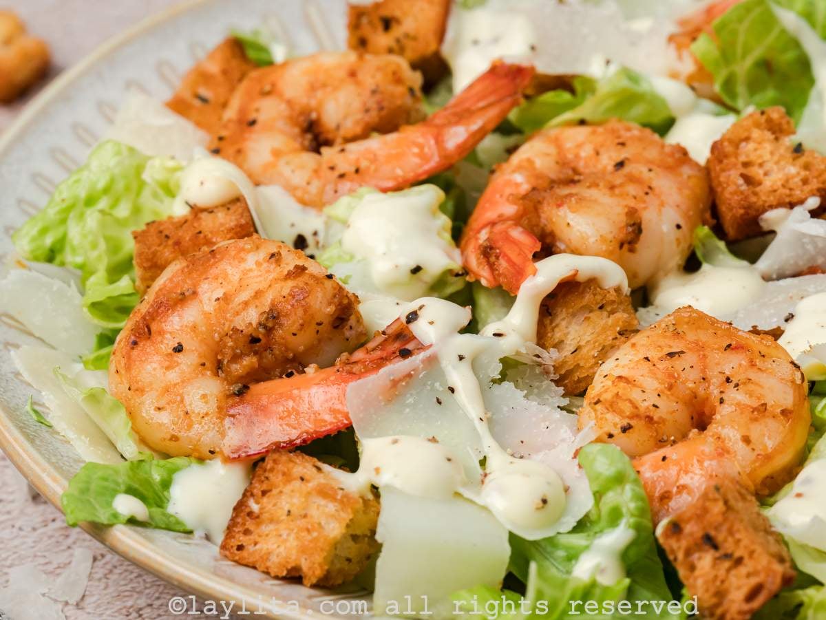 Close up of a plate of salad topped with Shrimp and a creamy salad dressing