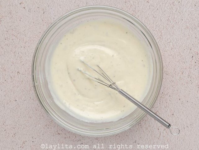 Ingredients for Caesar dressing being whisked in a glass bowl