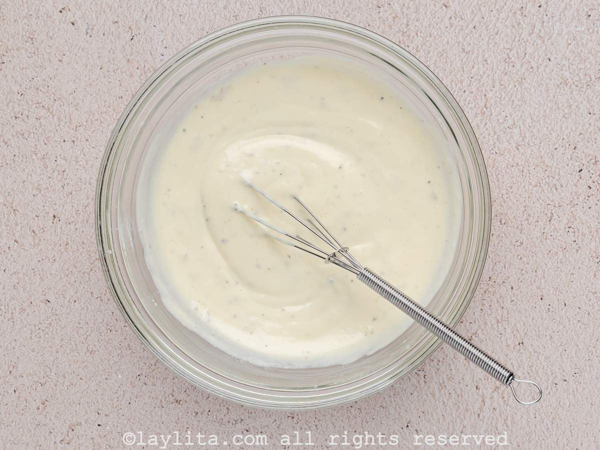 Ingredients for Caesar dressing being whisked in a glass bowl