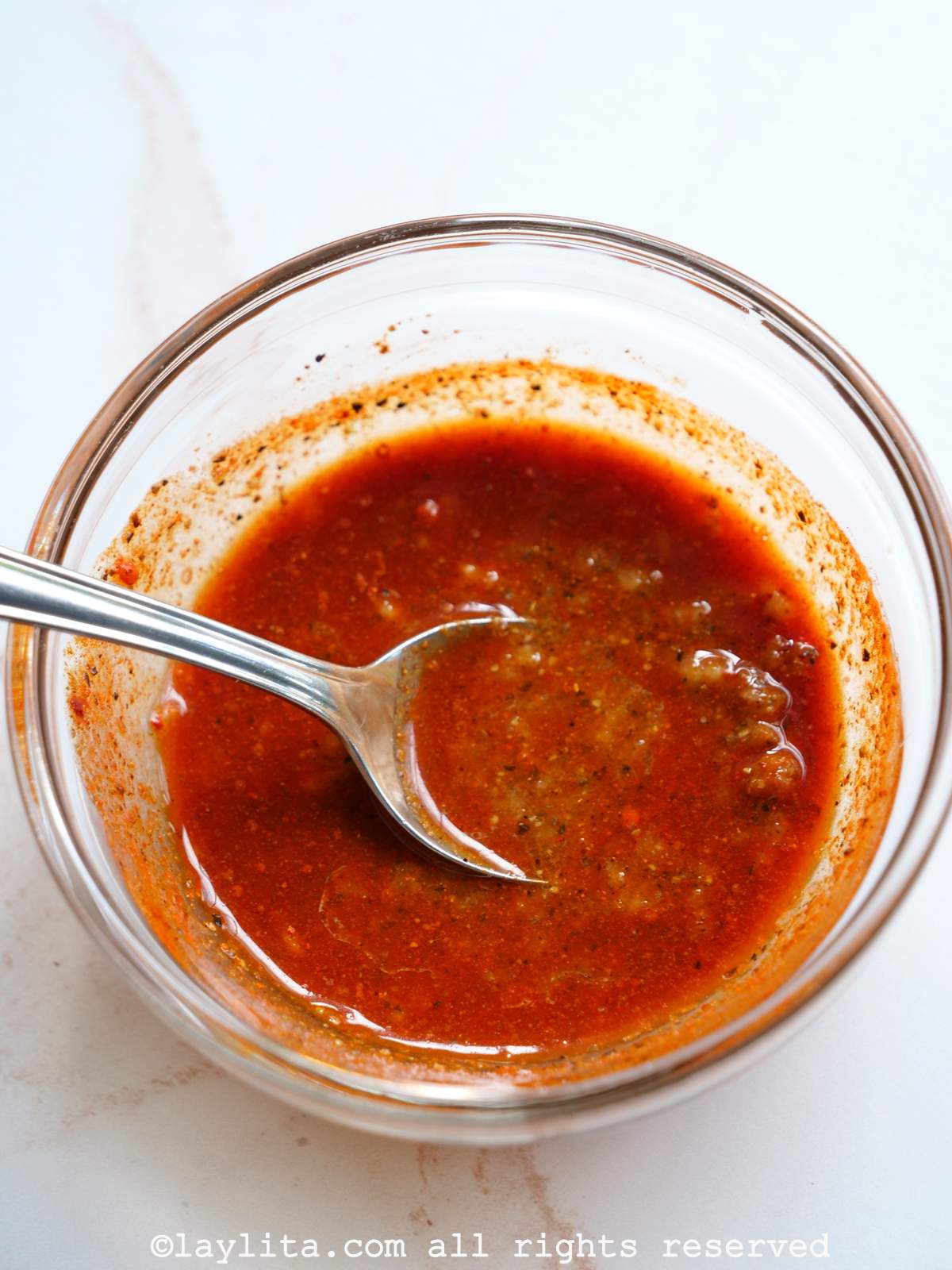 Achiote garlic marinade in a glass bowl with a spoon