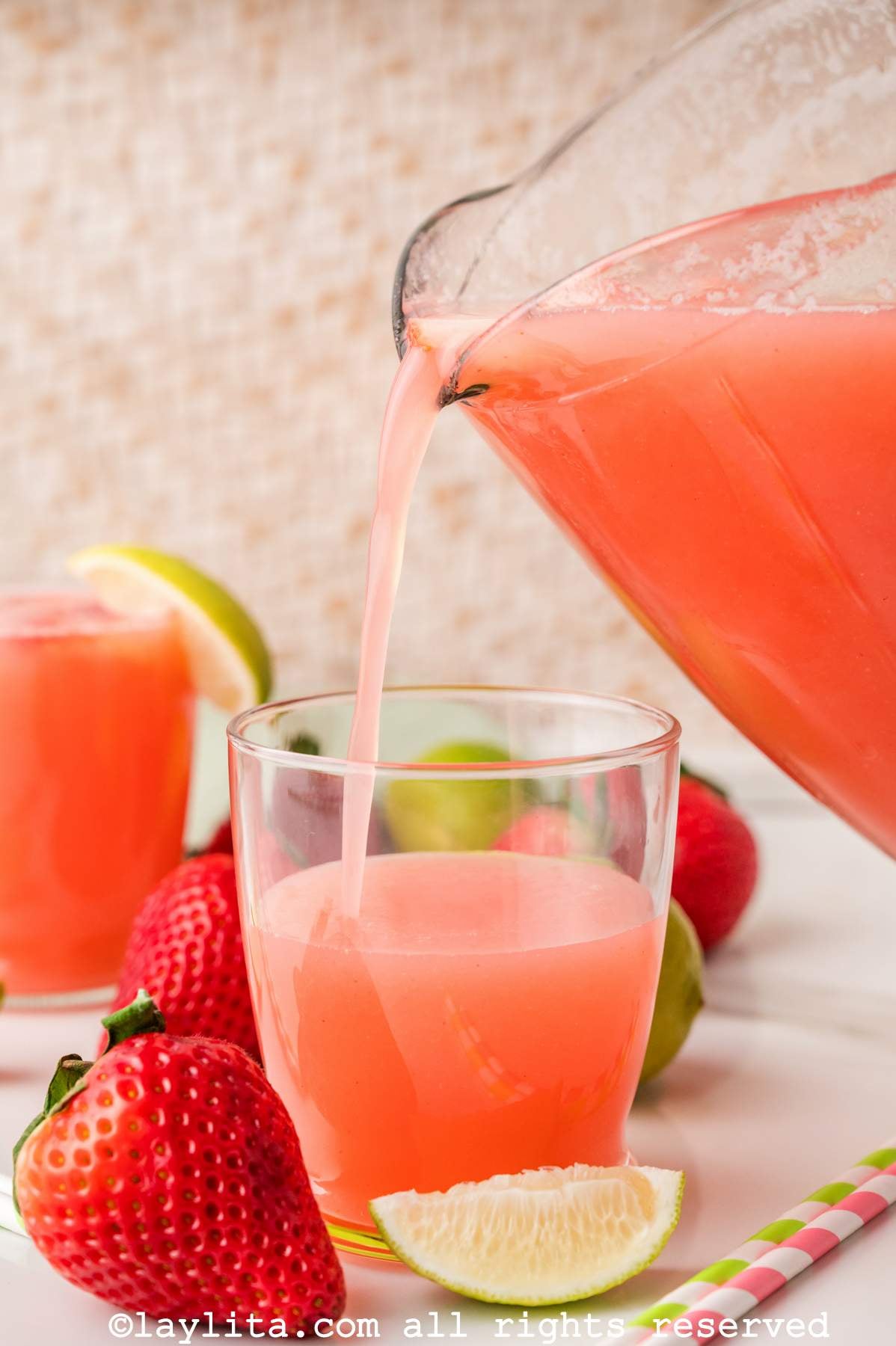 Pouring a glass of strawberry agua fresca from the pitcher.