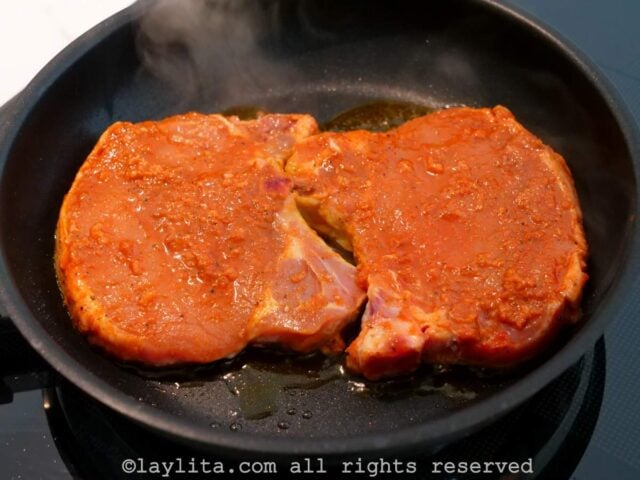 Pork chops cooking in a pan