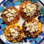 Four torrejas de choclo on a plate with crumbled queso fresco on top