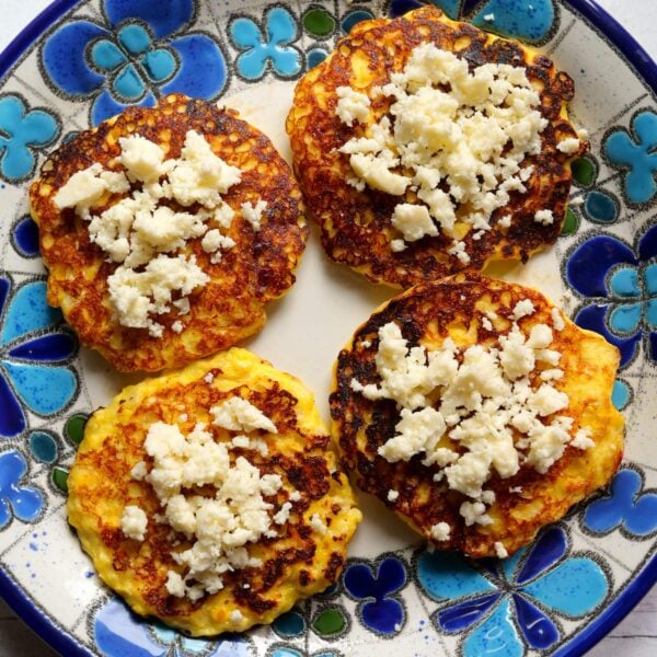 Four torrejas de choclo on a plate with crumbled queso fresco on top