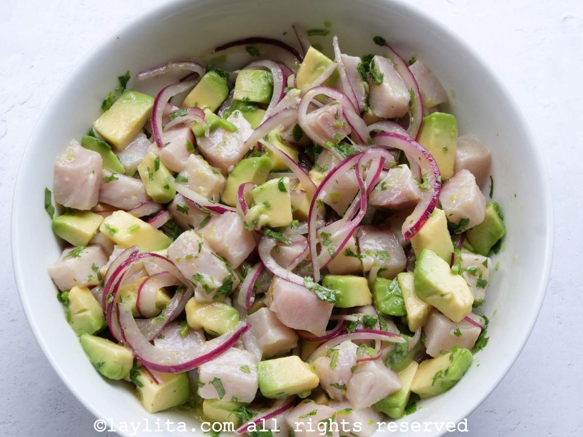 A white bowl with hamachi or yellowtail tuna ceviche mixed with avocado and red onions