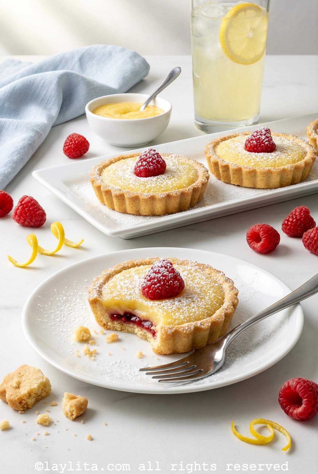 Raspberry lemon tartlet served on a plate with one bite missing from the tart
