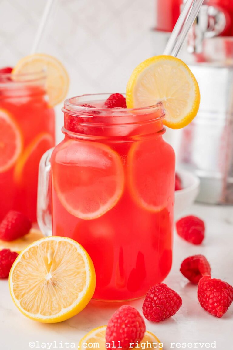 Side view of a jar of raspberry lemonade, garnished with lemons and a straw.