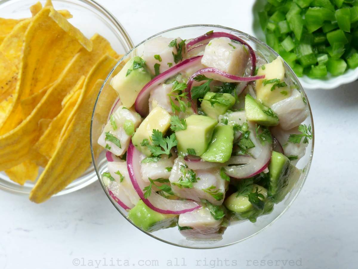 Hamachi ceviche in a glass with a bowl of plantain chifles and jalapeños next to it.