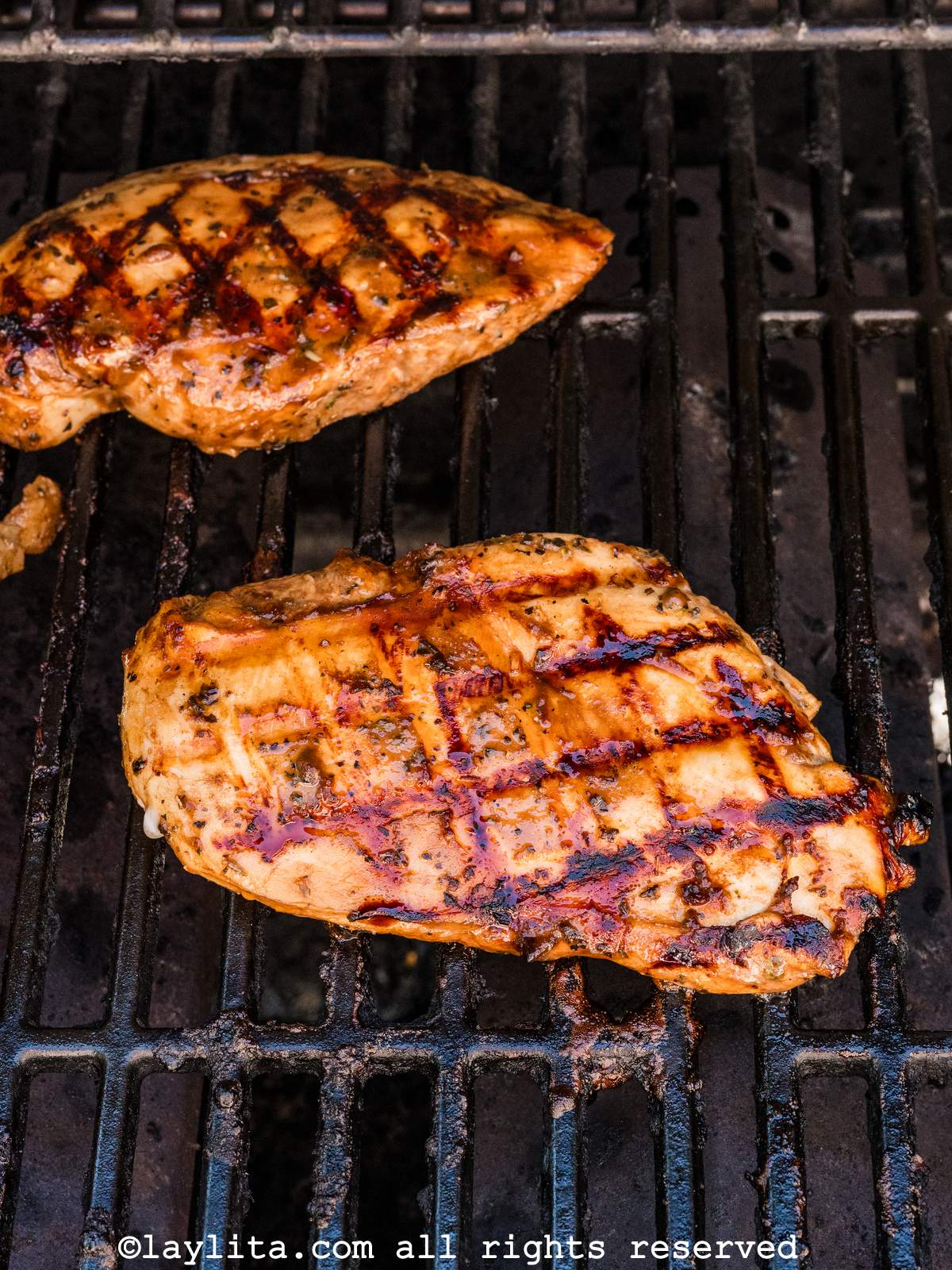 Two chicken breasts cooking on the grill