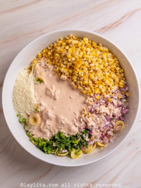 Grilled corn kernels, cooked pasta, onions, cilantro and cotija cheese with a creamy chipotle dressing in a bowl