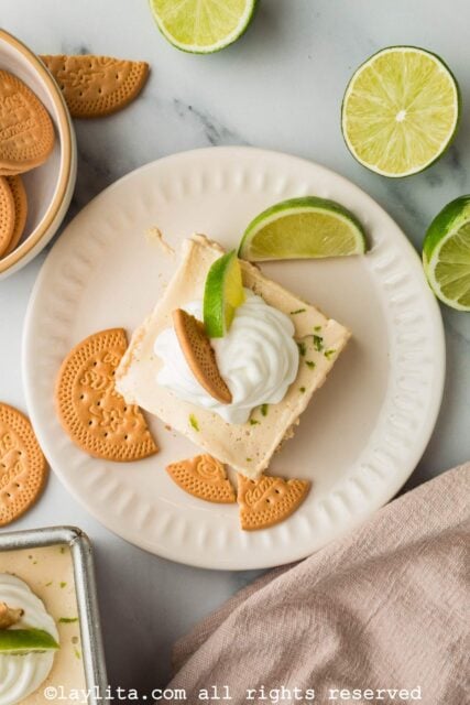 Overhead view of a slice of Mexican lime icebox cake on a plate with cookies and a lime wedge
