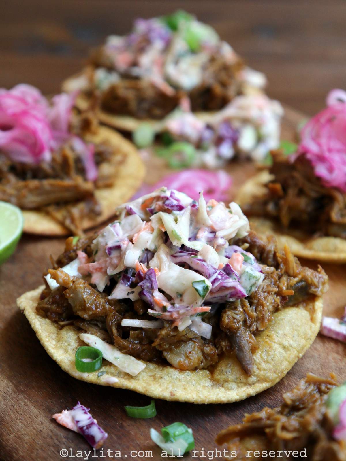 Side view of a tostada served with chicha pulled pork and coleslaw on top.