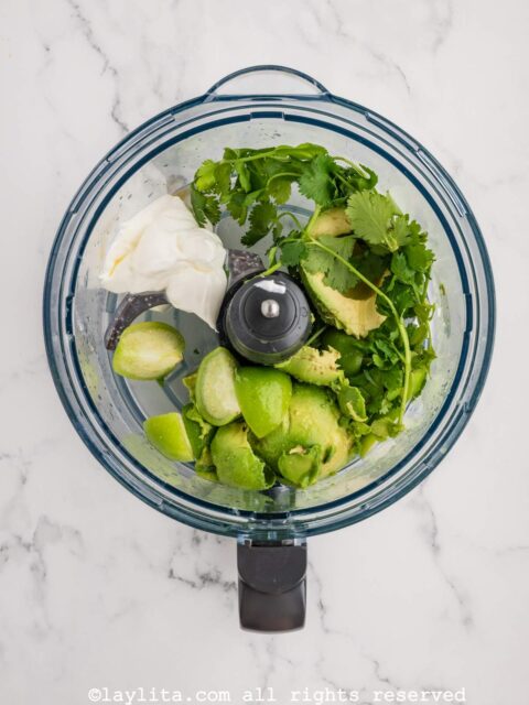 Ingredients for avocado tomatillo salsa in a food processor bowl