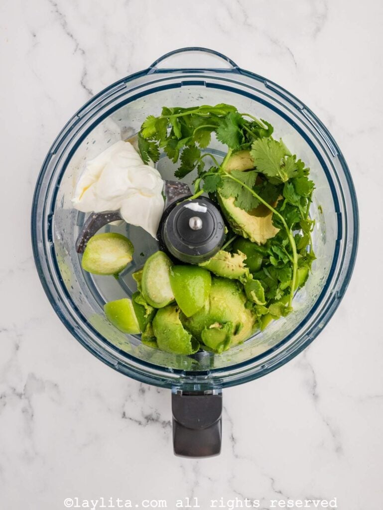 Ingredients for avocado tomatillo salsa in a food processor bowl