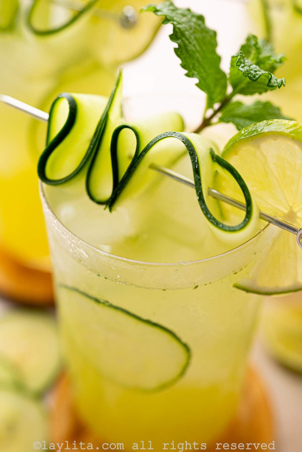 Close up view of a cucumber lime drink decorated with a cucumber ribbon and mint leaves