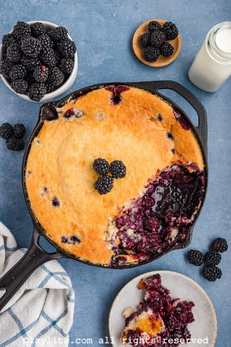 Overhead shot of blackberry cobbler in a cast iron skillet with some missing from the skillet.