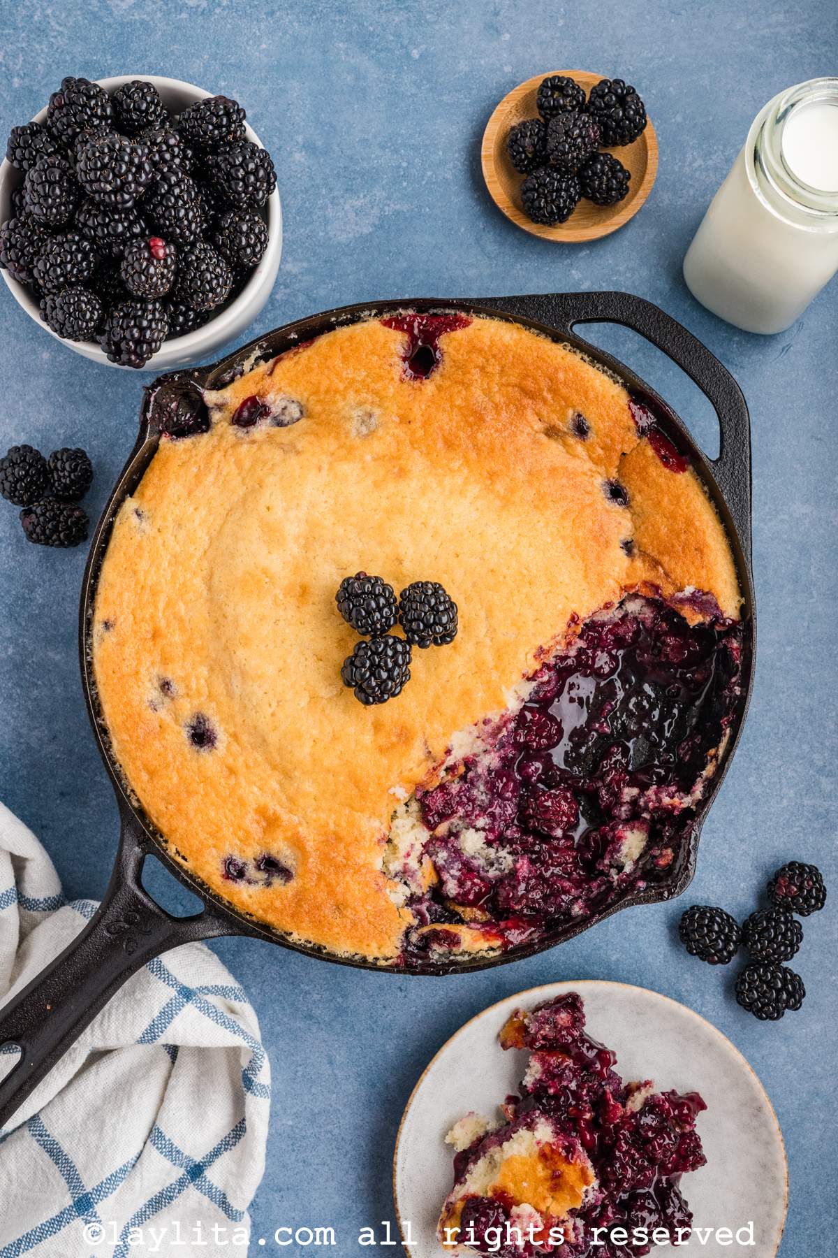 Overhead shot of blackberry cobbler in a cast iron skillet with some missing from the skillet.