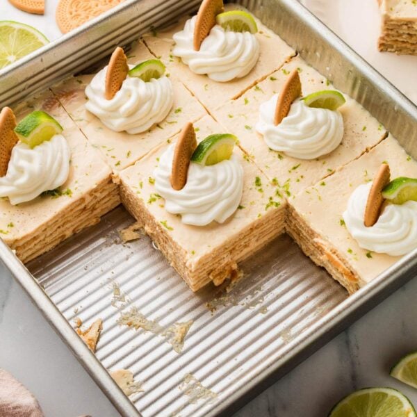 Carlota de limón in a baking dish with each slice decorated with whipped cream and cookies.