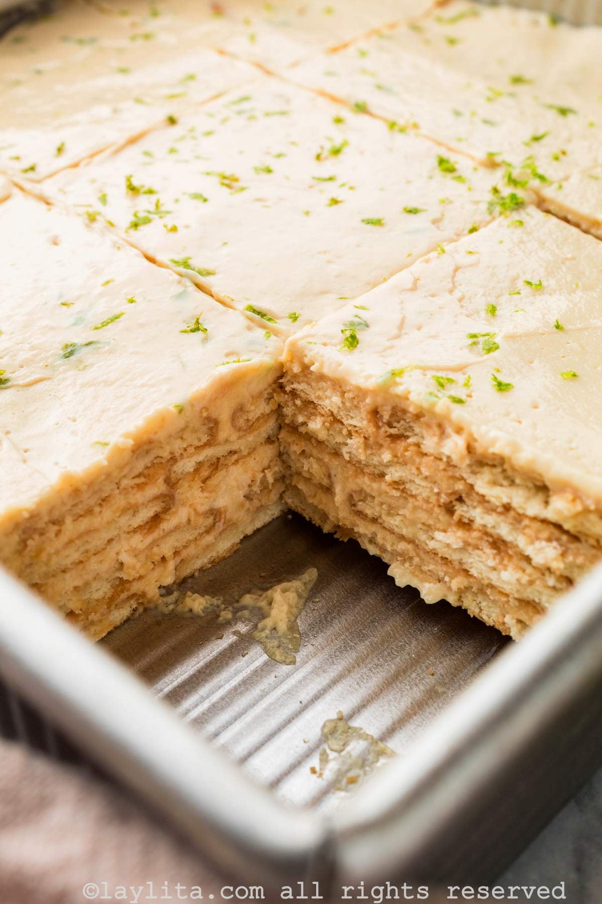 View of a Mexican Carlota or Lime Icebox cake in a pan with a slice missing 