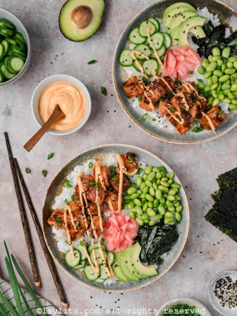 Overhead shot of two bowls of crispy salmon sushi bowls with spicy mayo drizzle on top.
