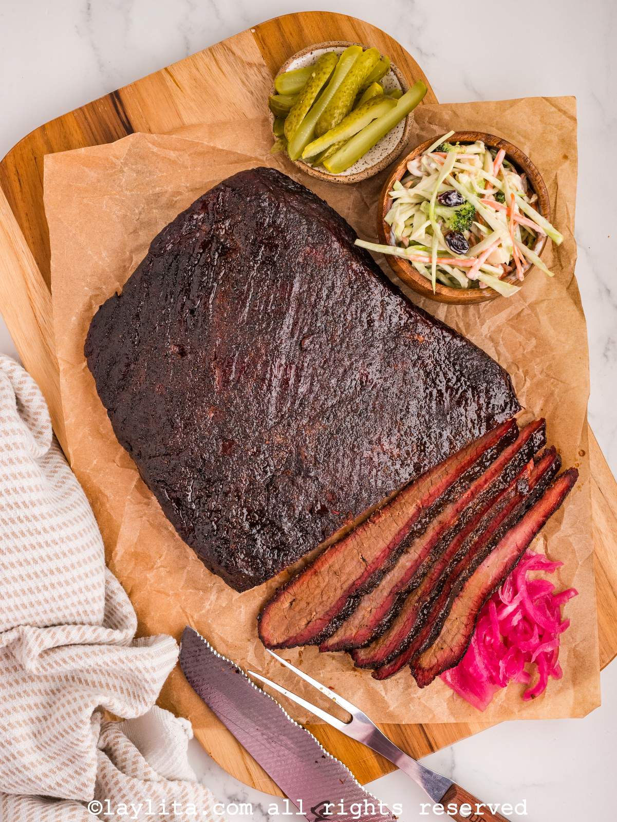 Overhead shot of brisket with some slices off the end next to pickled onions and pickles.
