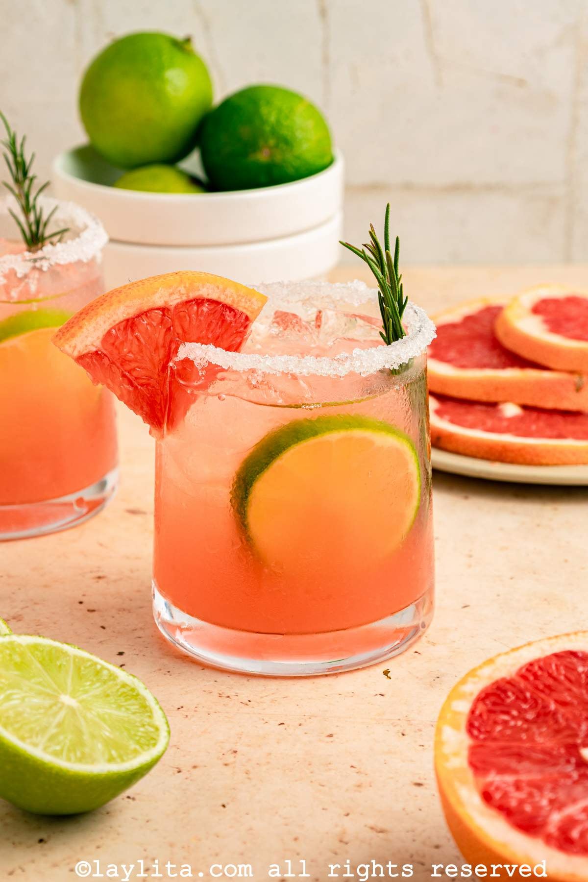 Paloma cocktail on a counter next to slices of grapefruit stacked on top of each other.