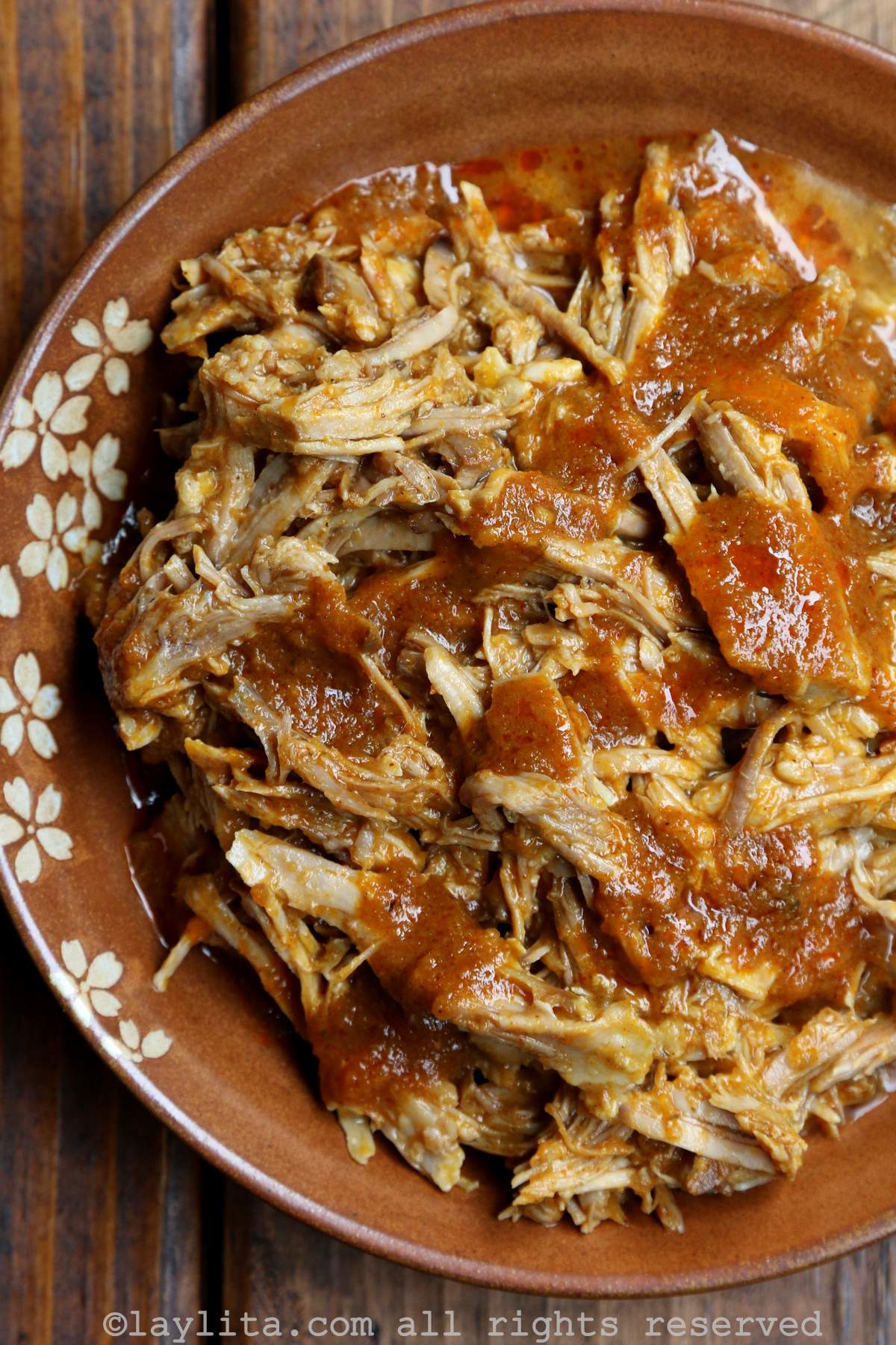Overhead shot of chicha pulled pork in a brown bowl with a flower design.