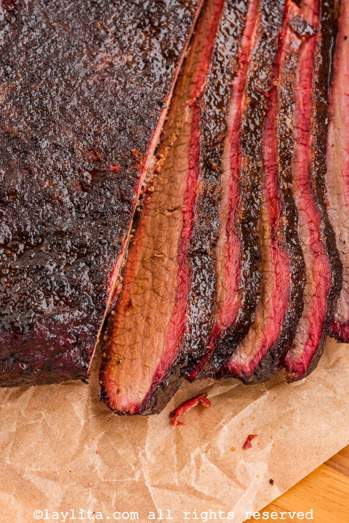 Closeup view of several slices of beef brisket on a piece of parchment paper