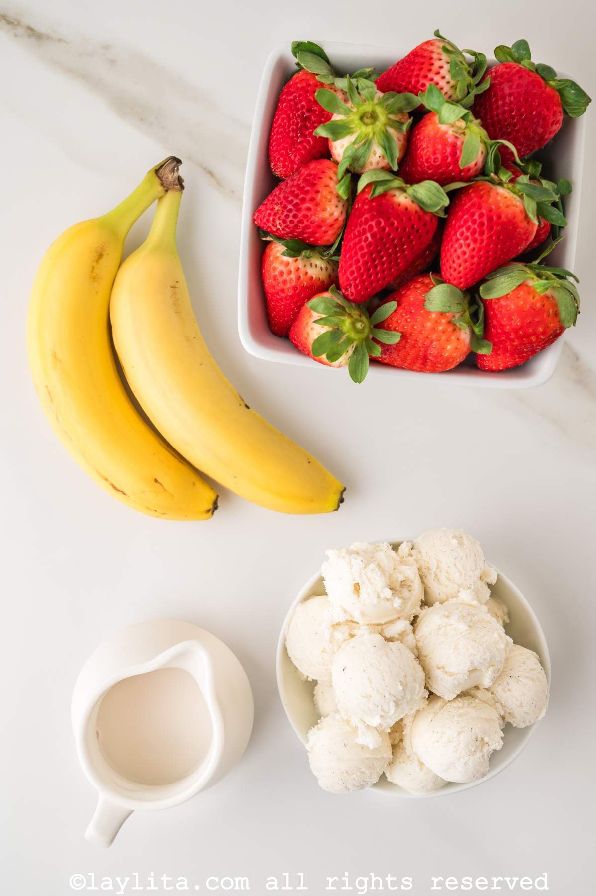 Ingredients for Strawberry Banana Milkshakes on a kitchen counter