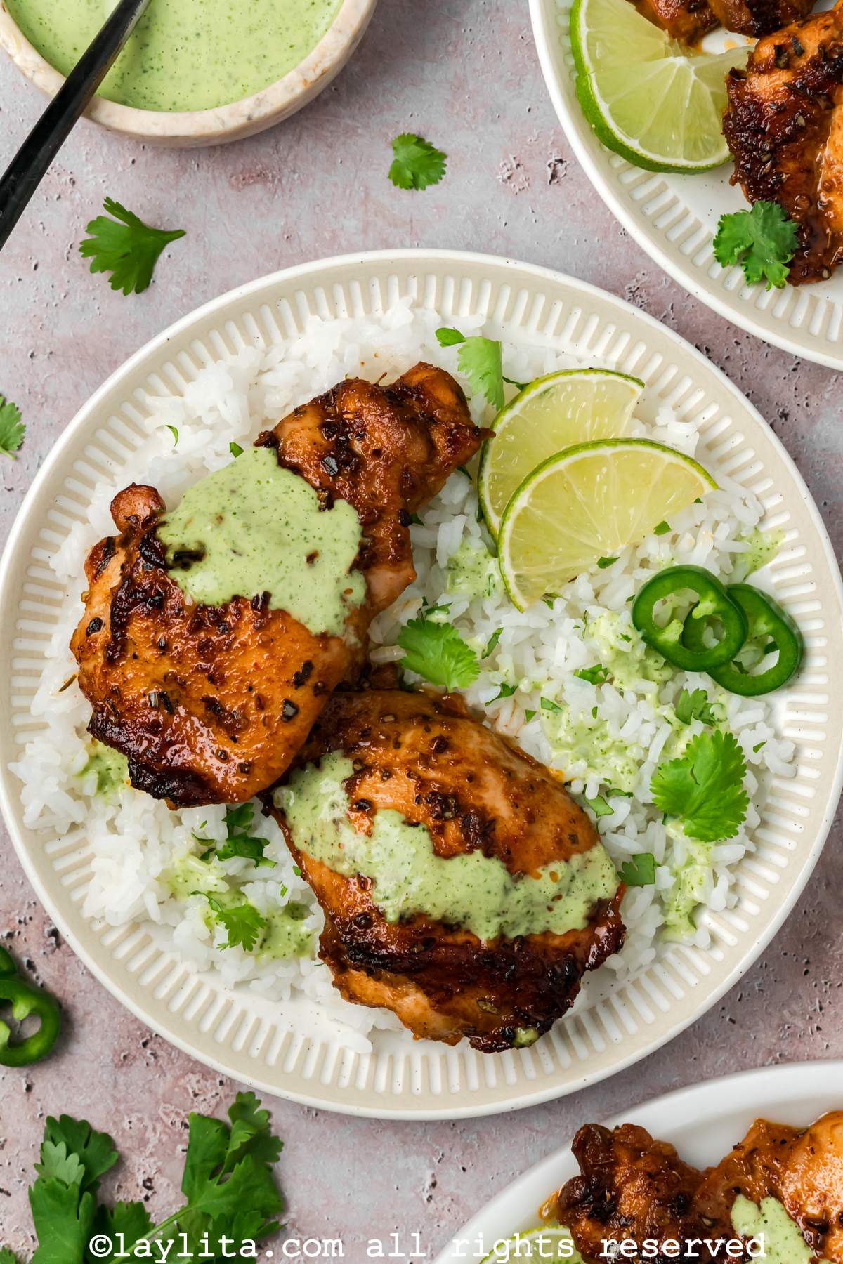 Peruvian chicken thighs served on a plate with rice and lime wedge on the side