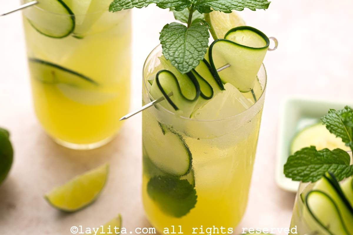 View of two glasses of cucumber lime agua fresca decorated with slices of cucumber and mint leaves