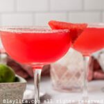Side view of two watermelon margaritas in coupe glasses, both garnished with sugar and watermelon.