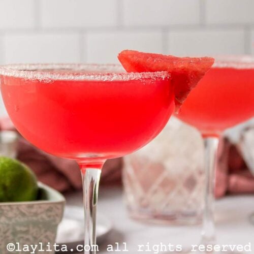 Side view of two watermelon margaritas in coupe glasses, both garnished with sugar and watermelon.