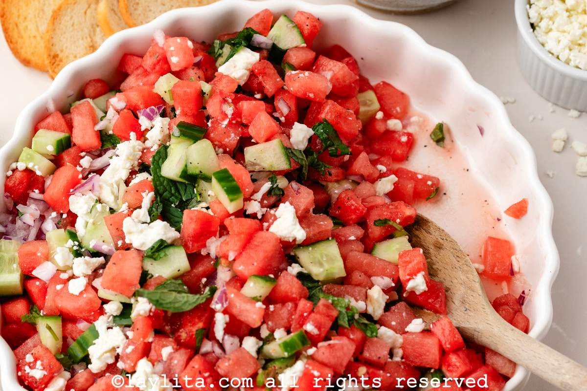 Closeup of a bowl of a watermelon salad with a serving spoon in the bowl