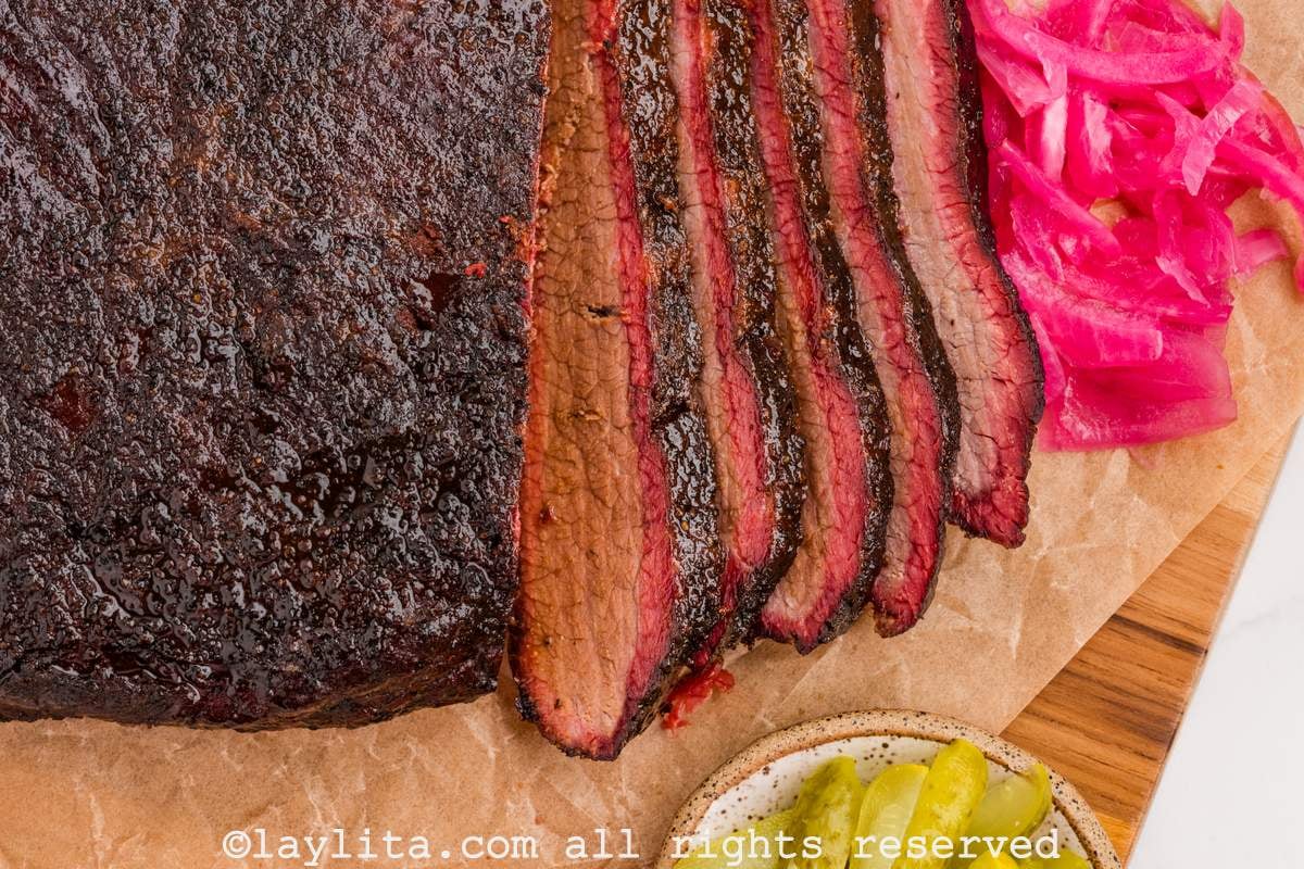 Closeup shot of brisket with some slices off the end next to pickled red onions