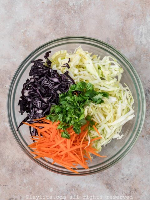 Ingredients for cabbage slaw in a glass bowl