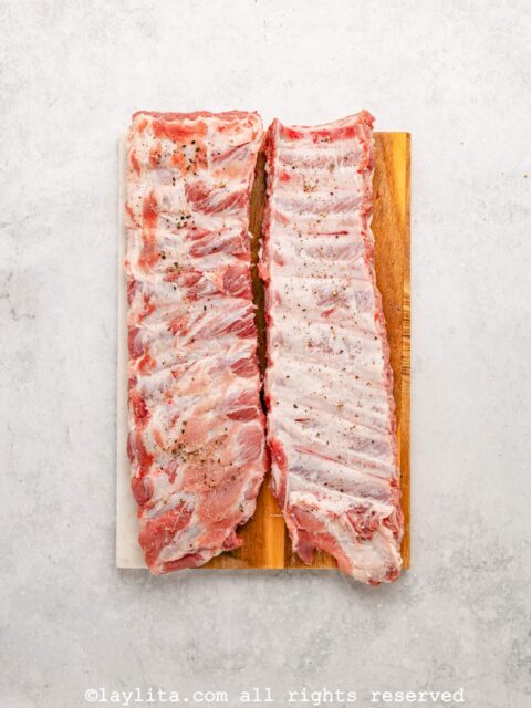 Two racks on uncooked pork ribs on a cutting board