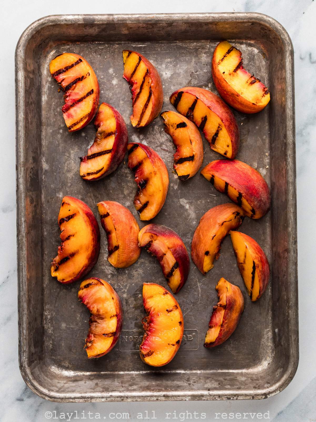 Grilled peach slices on a baking sheet