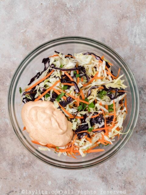 Preparing cabbage slaw in a glass bowl