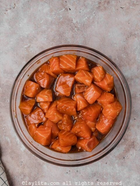 Salmon pieces marinating in a sauce in a glass bowl