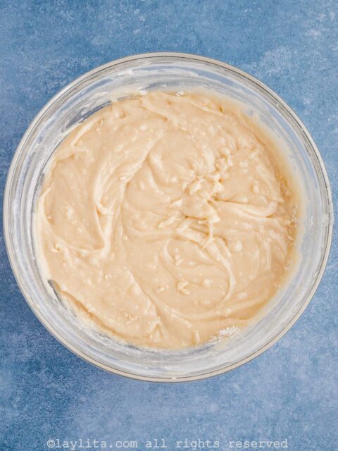 Batter for cobbler in a clear glass bowl on a blue surface