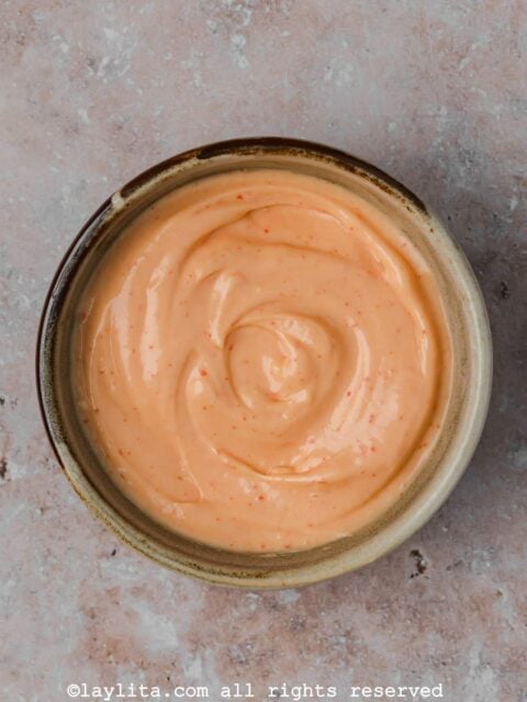 Overhead view of a bowl of spicy mayo on a concrete counter