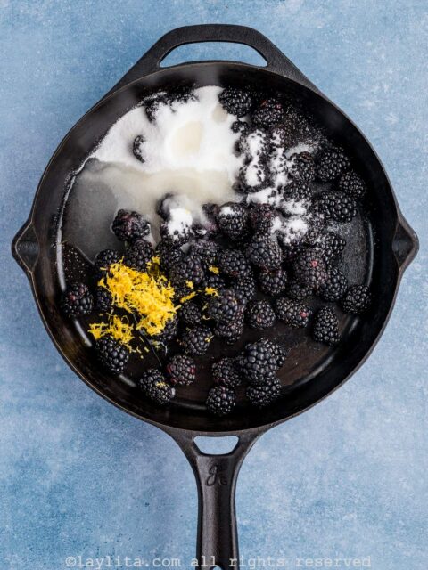 In a 10-inch cast iron skillet, add half of the blackberries (12 oz), sugar, salt, and lemon zest and juice