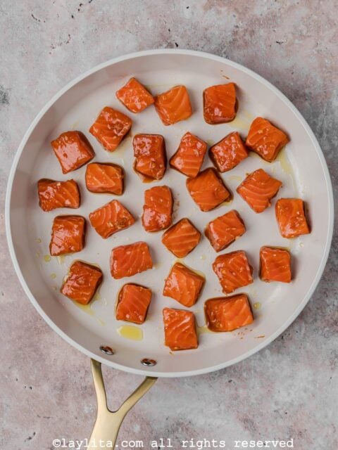 Cubed salmon pieces in a skillet before cooking