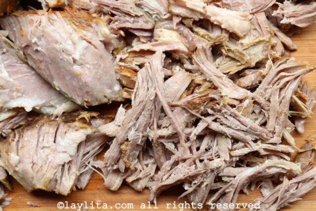 Shredding pulled pork shoulder on a cutting board