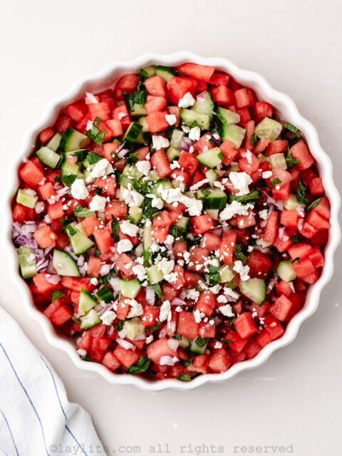 Overhead view of a watermelon feta salad in a white serving bowl