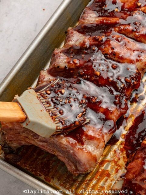Closeup shot of pork ribs being crushed with an Asian gochujang sauce