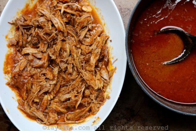 Pulled pork in a white bowl being mixed with a reduced sauce next to it